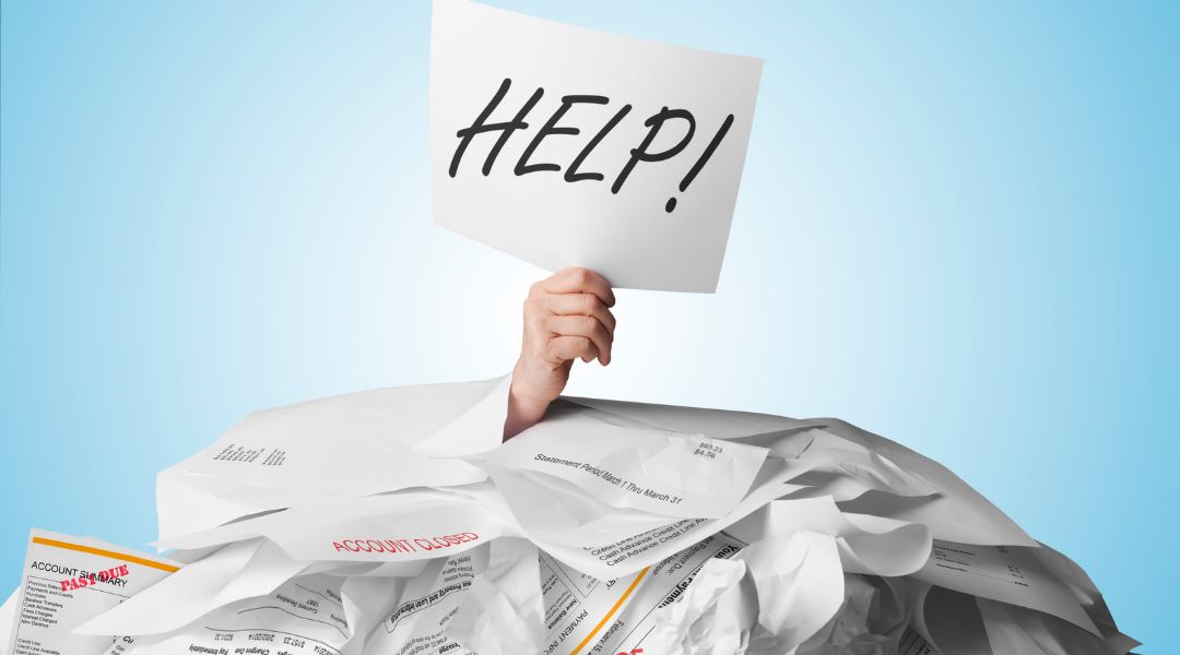 Hand with a help sign coming out of a mountain of bills - debt settlement company - tips from lawyer Stephanie Krane-Boehmer.